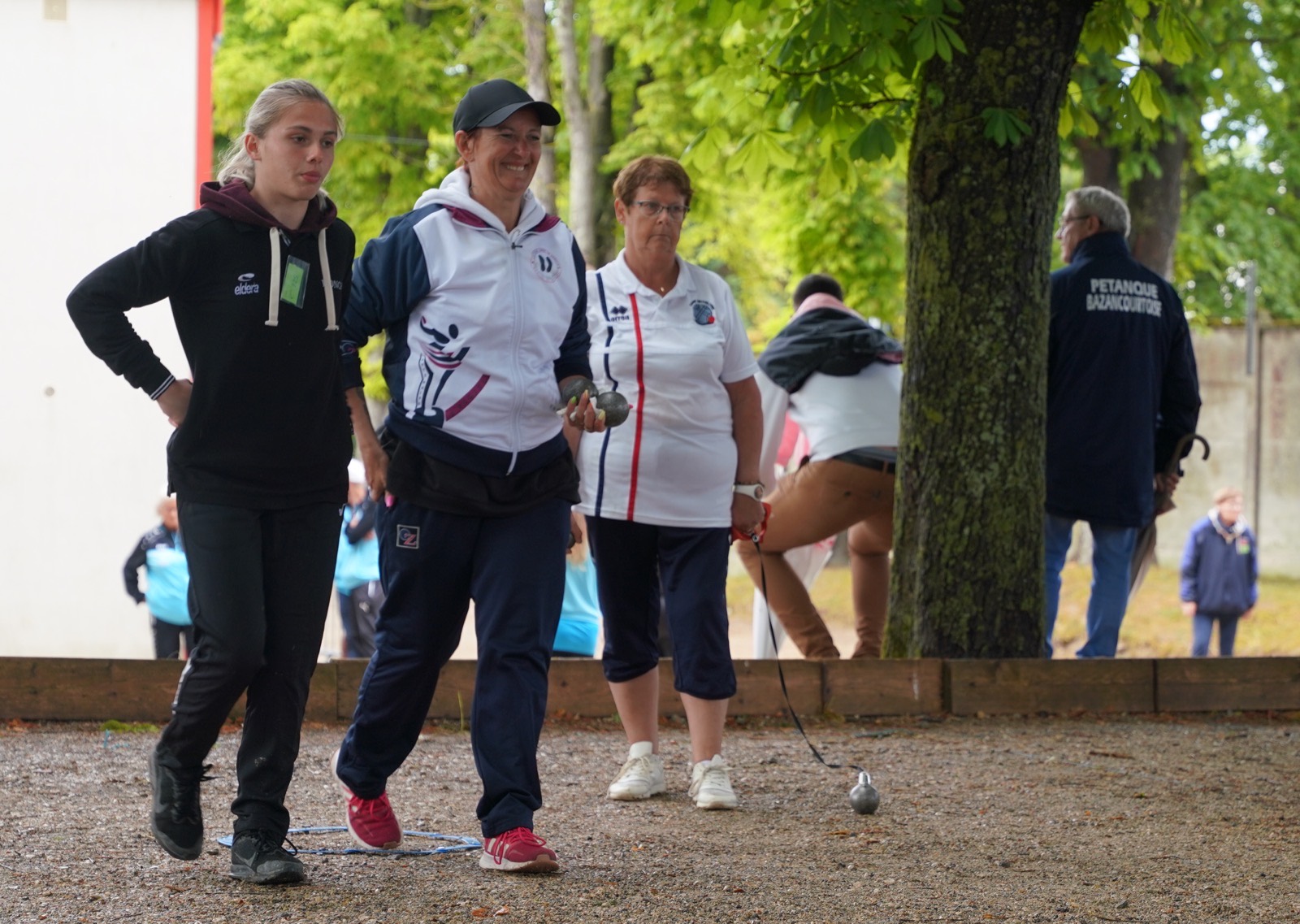 Joueuses et joueurs de pétanque de plusieurs générations sur un terrain de village